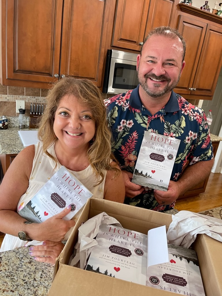 Jim and Shannon Pourteau standing in a bookstore with a man holding their book, Hope Is Where the Heart Is